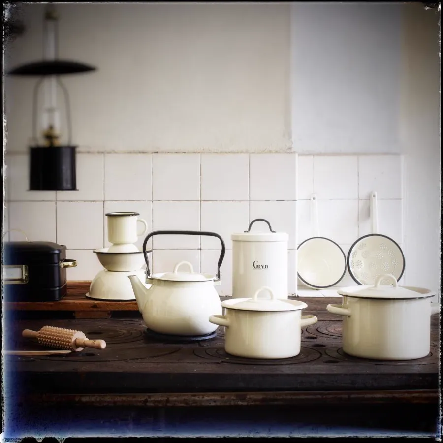 White enameled teapot, milk pan and pots in a vintage kitchen